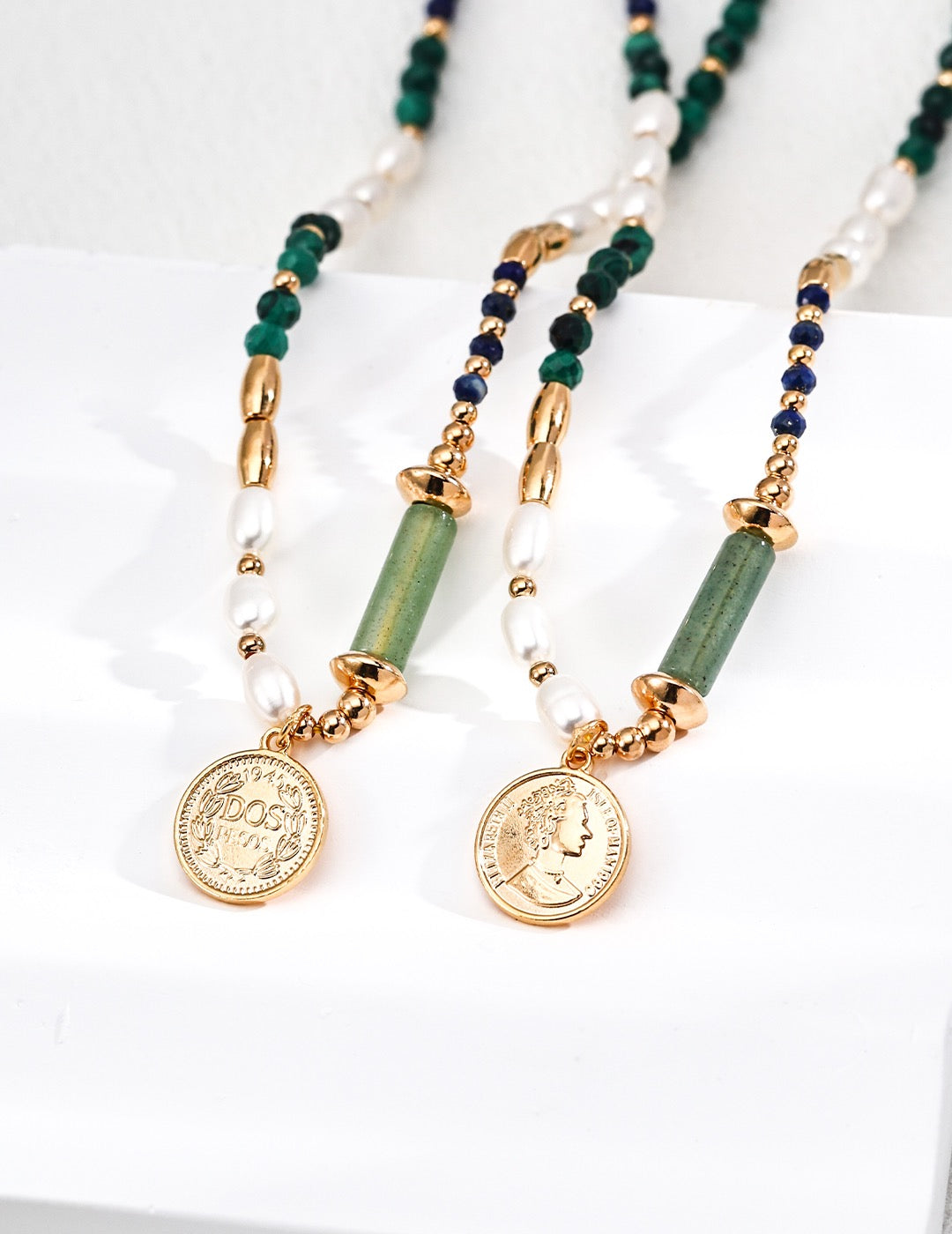 Necklace with gold coins, green and blue beads on a white background