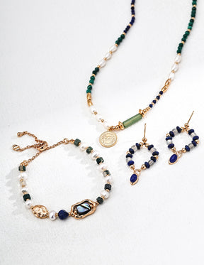Set of jewelry including necklace, bracelet, and earrings with green and blue beads on a white background