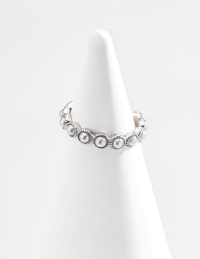 The Seraphina Adjustable Pearl Cuff Ring in Silver is displayed on a ring display stand with soft natural lighting, emphasizing its luxurious design.