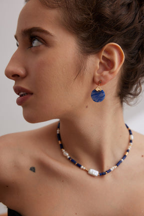 Woman wearing a Blue Aventurine earring and a Lapis Lazuli necklace against a neutral background