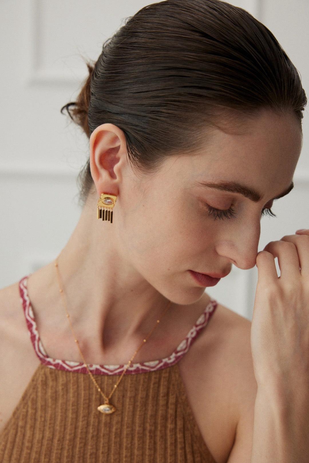 A woman wearing Inez Zircon Tassels Earrings with an 18k Gold Vermeil finish, along with a matching necklace.
