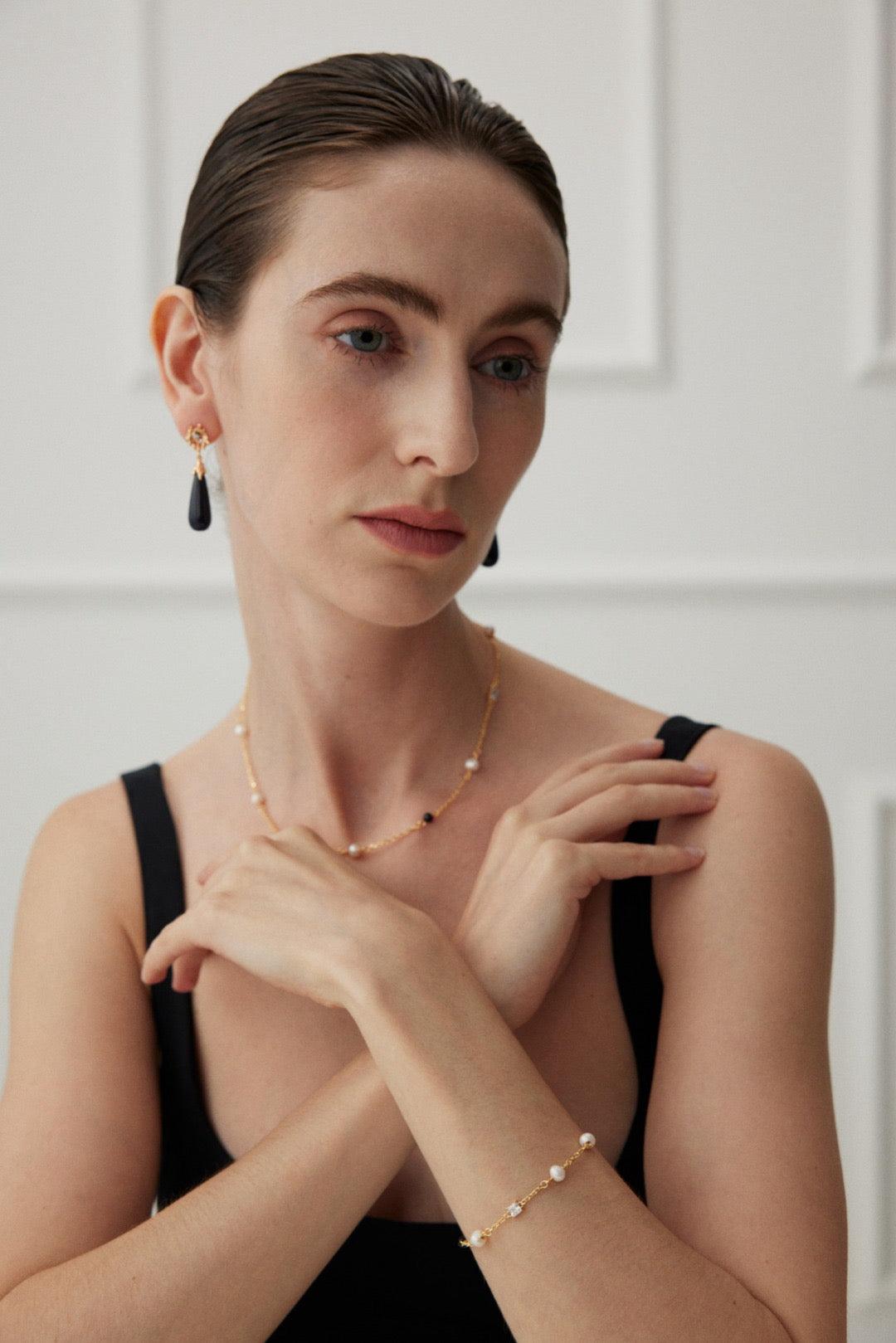 The model is wearing the Isla 18K Gold Freshwater Pearl Zircon Black Agate Jewelry Sets.