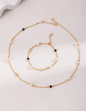 Isla 18K Gold Freshwater Pearl Zircon Black Agate Bracelet and Necklace, displayed on a marble surface with soft natural lighting, emphasizing its minimalist design.
