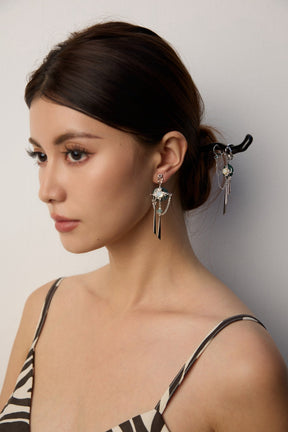 Woman wearing jade buckle drop earrings and a jade buckle hair stick with zebra print top with a neutral background.