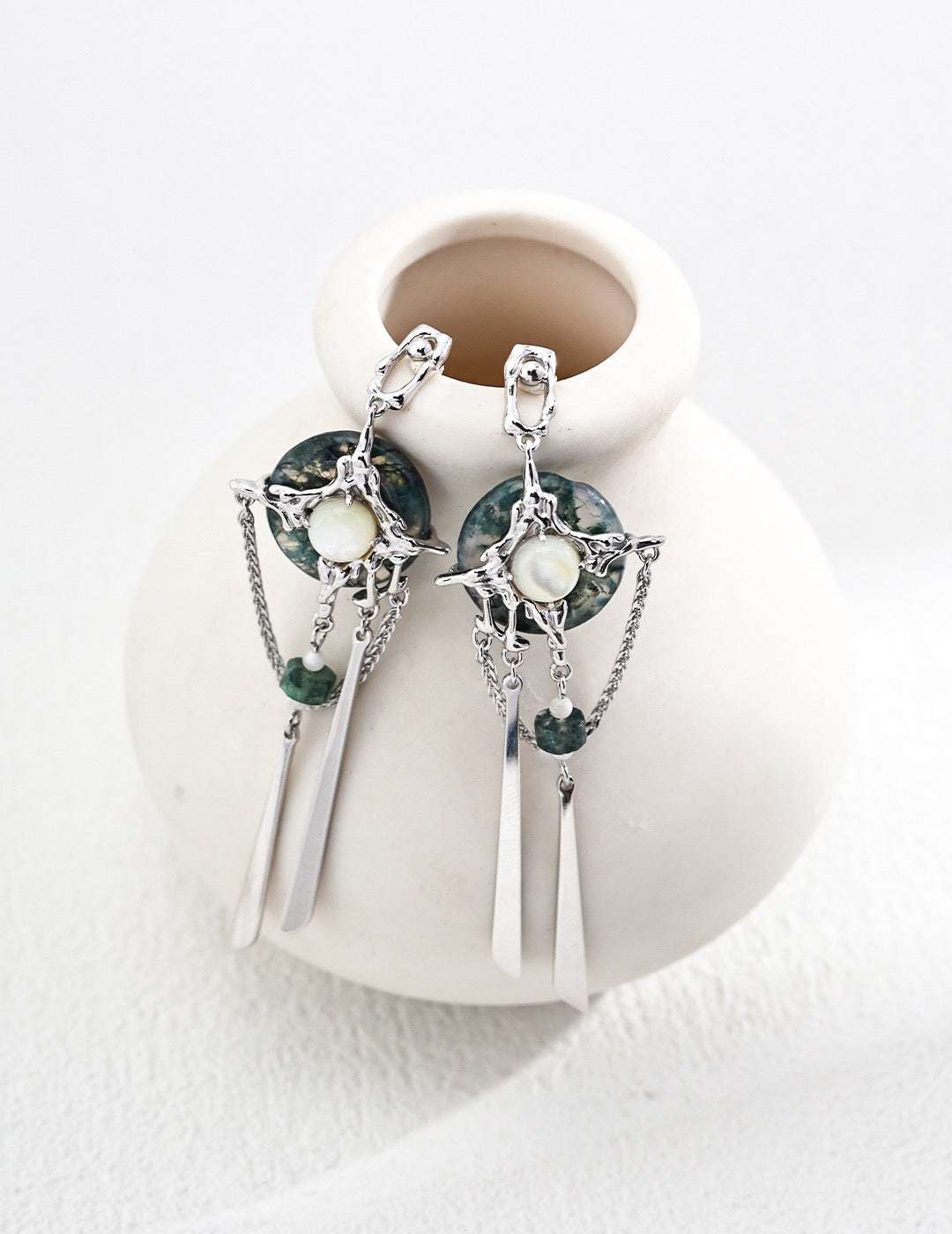 A pair of drop earrings with a floral pearl design, featuring a mix of silver and green colors, displayed against a white background.