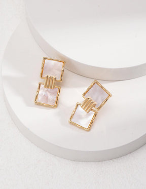 Karina Drop Earrings are displayed on two white circular stages.
