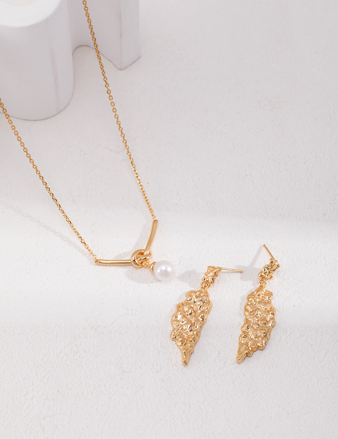 Gold necklace and earrings on a white background