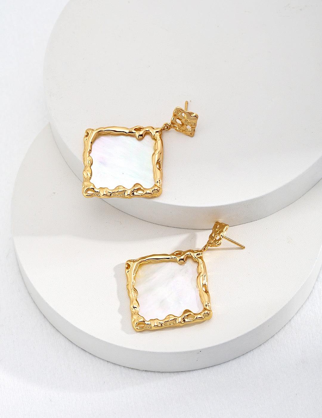 Larina Earrings displayed on two white circle stage.