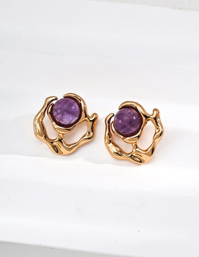Pair of gold earrings with purple gemstones on a white background