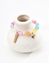 Colorful Lucky Day gemstone bracelet featuring pastel glass beads, freshwater pearls, and gold vermeil heart and charm details, styled on a neutral ceramic vase.