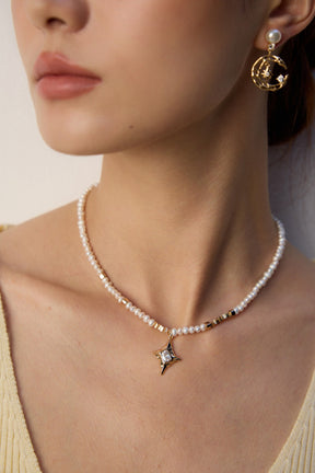 Pearl necklace with a star pendant worn by a person against a neutral background