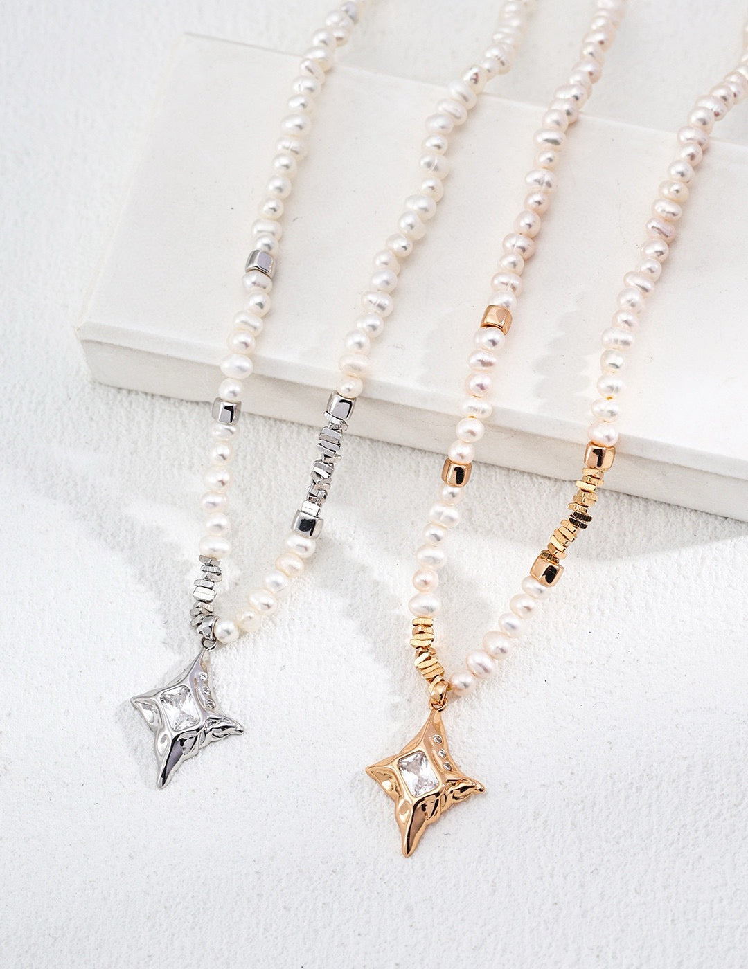Three pearl necklaces with star-shaped pendants in silver, gold, and rose gold on a white background.