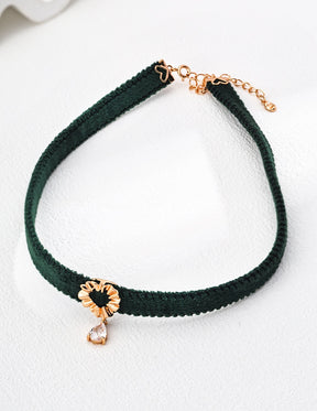 Lumina Heart Drop Choker Necklace in green velvet with a gold heart-shaped centerpiece and teardrop zircon pendant, displayed on a white backdrop.