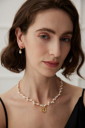 The Luna Drop Earring is paired with a dainty freshwater pearl necklace, creating an elegant and minimalist look.