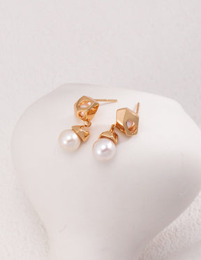 A close up of the Luna Pearl Drop Earrings in 18k Gold vermeil displayed on the white rock, showcasing the shine of the pearls.