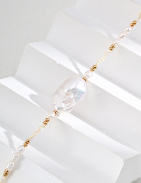 Close up of the large baroque pearl pendant necklace with gold beads and freshwater pearls displayed on the withe stage. 