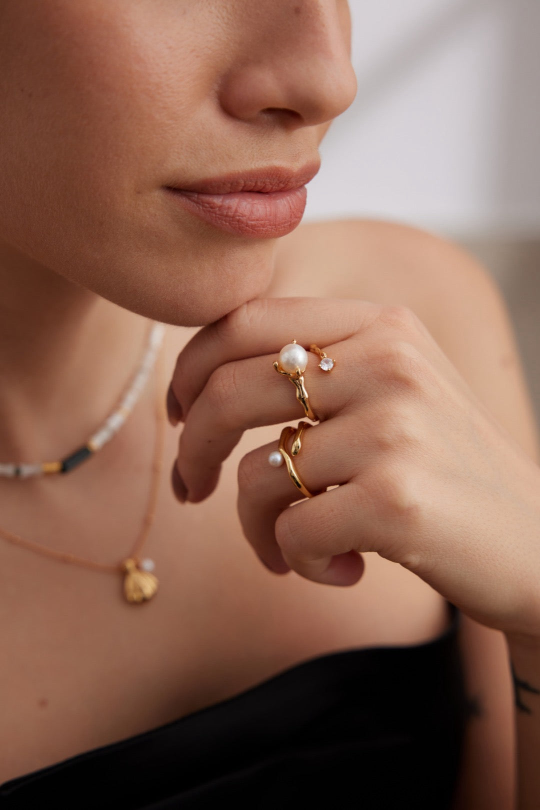 A person wearing a stackable open ring with an 8mm pearl and zircon inlay on their finger.