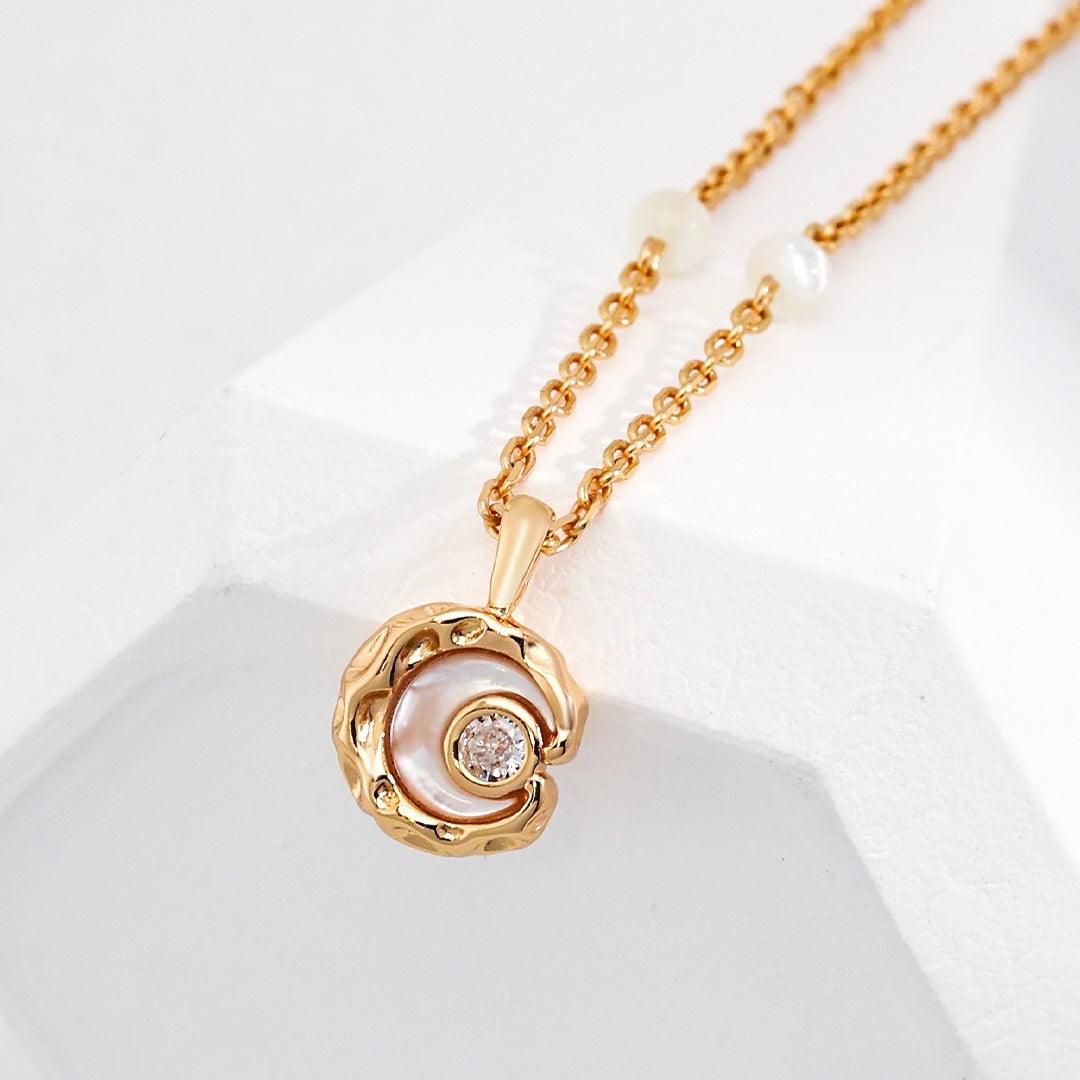Close-up of the Rayna Necklace displayed on the white rock, showcasing the mother of pearl pendant with a zircon inlay.