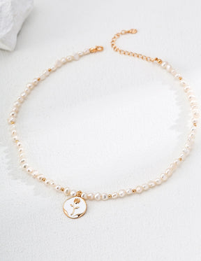 Pearl necklace with a gold hand-painted rosecharm on a white background