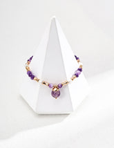 Necklace with purple and gold beads on a white stand against a white background