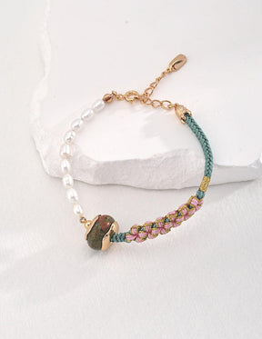 RuYi Bracelet is displayed on the white rock, showcasing the details of the Unakite, pearls, and the complexion and layer of the braid on the bracelet.