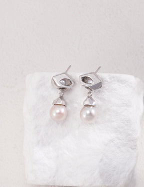 The Silver Luna Pearl Drop Earrings hanged on the white rock.