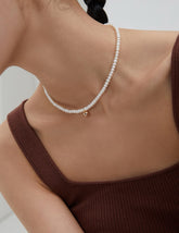 5mm freshwater pearl strand with gold bead pendant necklace wear by a woman in a brown knit tank top