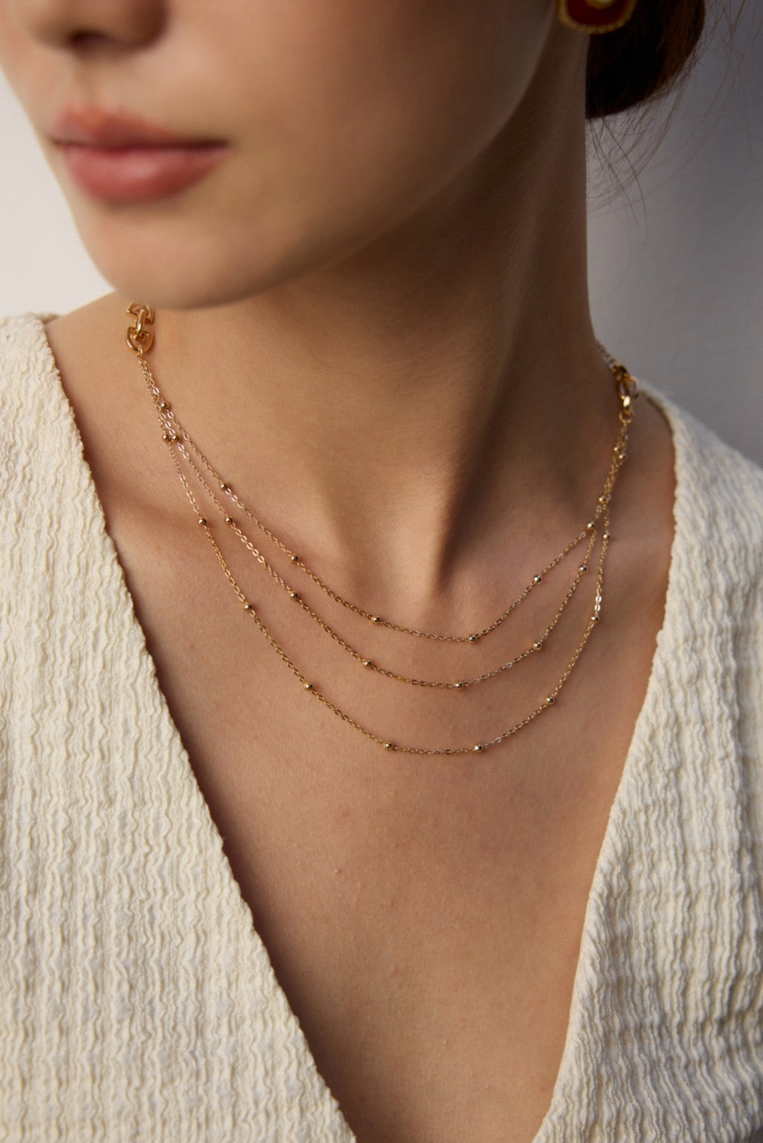 Gold necklace on a person wearing a textured white top