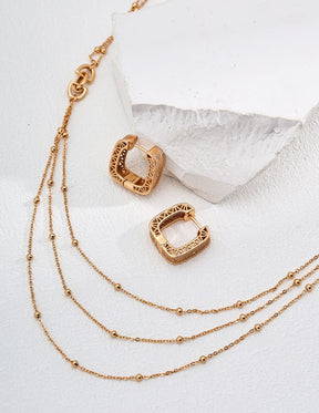 Gold hoop earrings with a gold chain on a white background