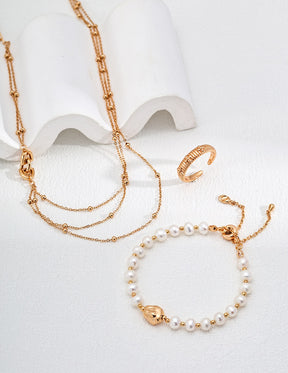Gold necklace, bracelet, and ring on a white background