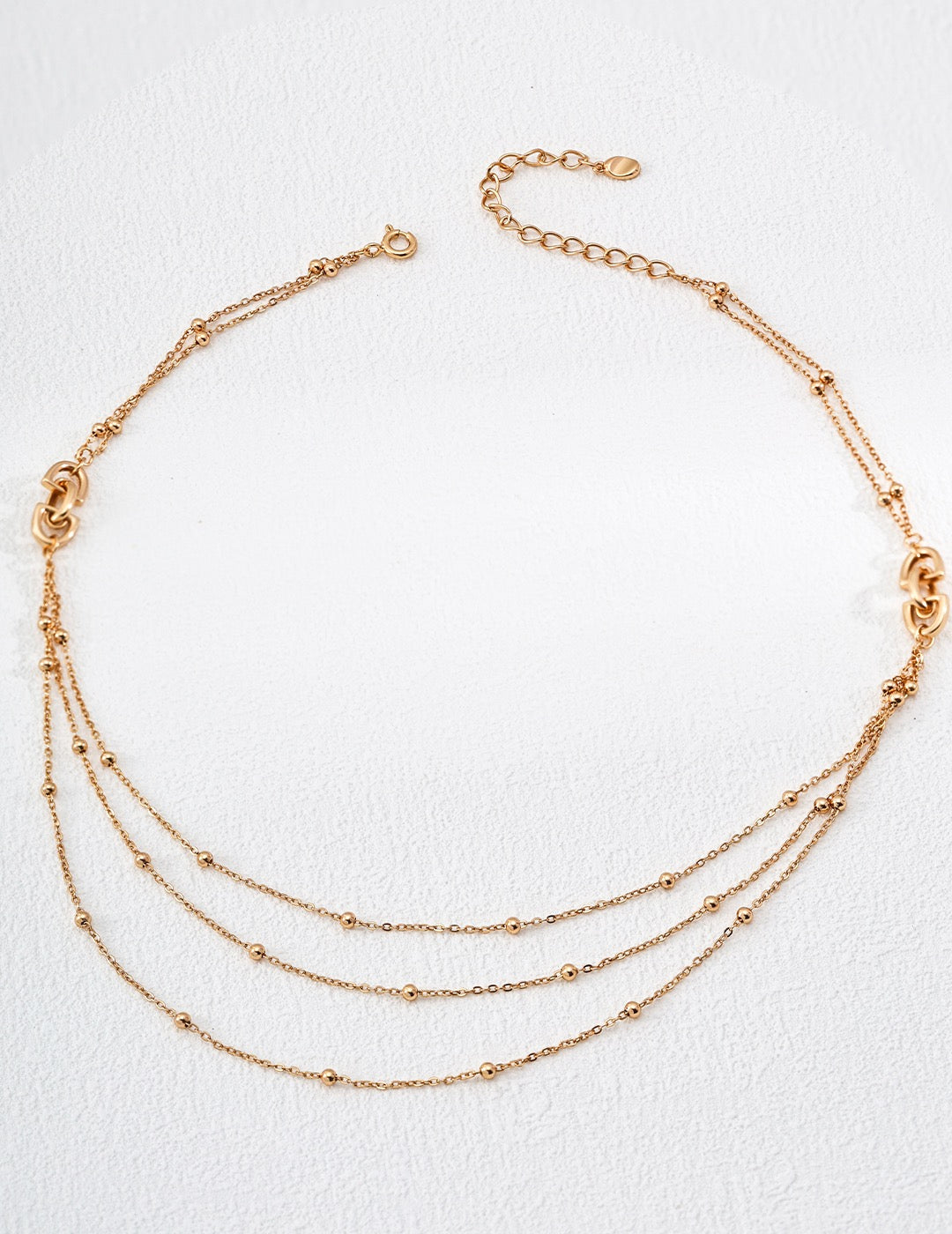 Gold necklace with multiple strands on a white background