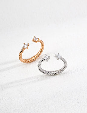 Two Twilight Twist Open Rings in gold and silver with twisted band design and zircon stone ends, displayed on a white background.
