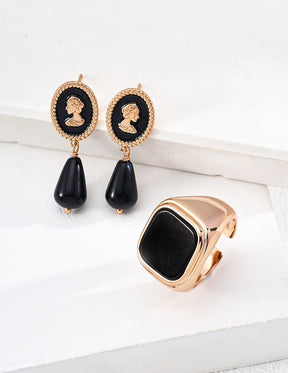 Pair of black teardrop earrings with gold accents on a white surface