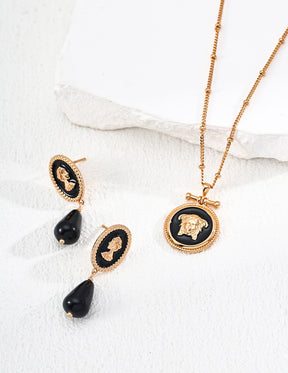 Vintage gold cameo necklace and earrings with black stones on a white fabric background