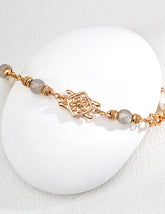 Gold bracelet with Labradorite on a white stone surface