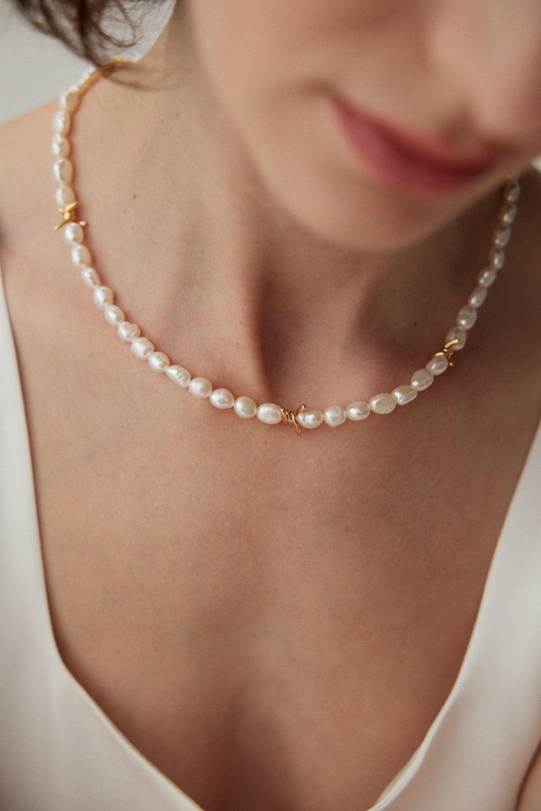 A close-up of a woman wearing a Vine Baroque Pearl Necklace with 18k Gold Vermeil accents around her neck.