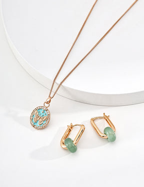 Rose gold Tiffany blue butterfly pendant necklace and earrings with green stones on a white background