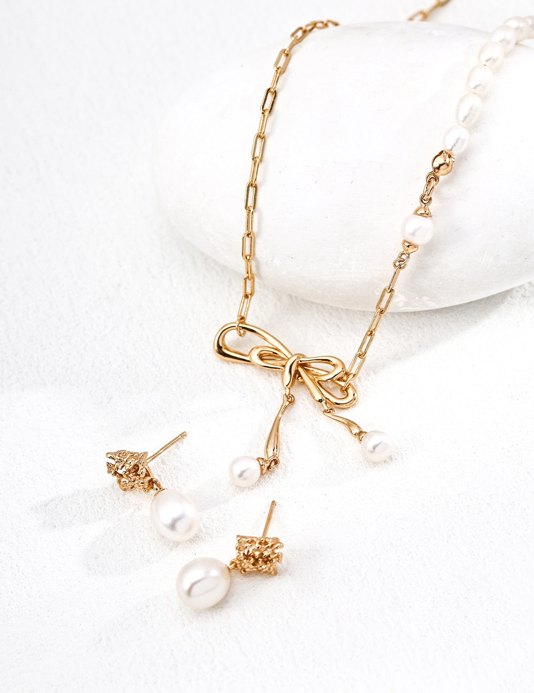 Camellia Freshwater Pearl Drop Earrings in 18K Gold Vermeil and bow pearl pendant necklace displayed on a white background.