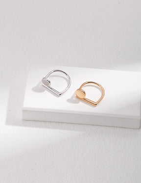 A gold and silver geometry Open Ring displayed on the white rock.