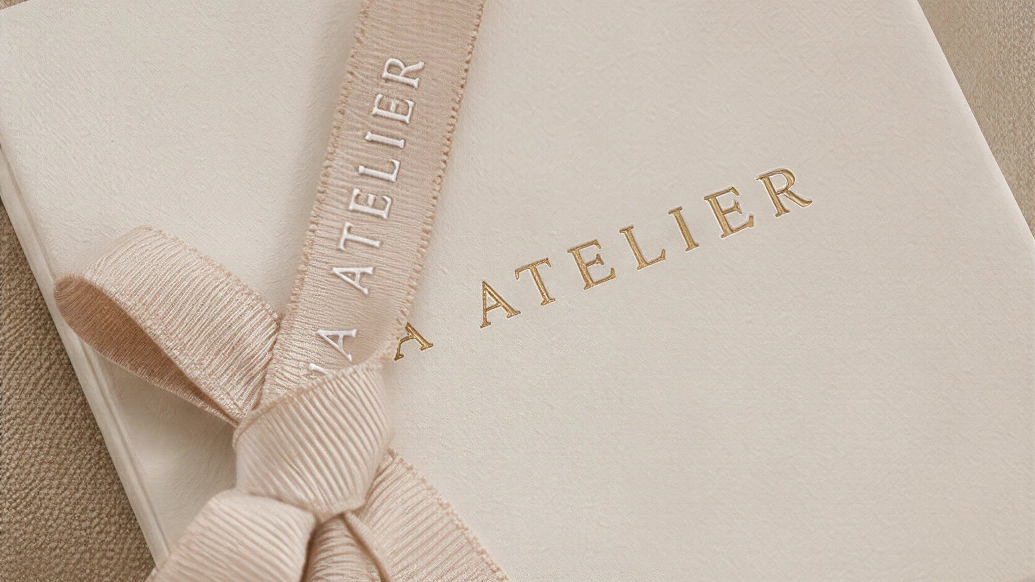 Gift box with a ribbon and 'LIA ATELIER' branding on a beige background.