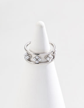 A close-up of the sterling silver open ring with a floral design adorned with small freshwater pearls, displayed on a white cone-shaped jewelry holder against a clean white background.